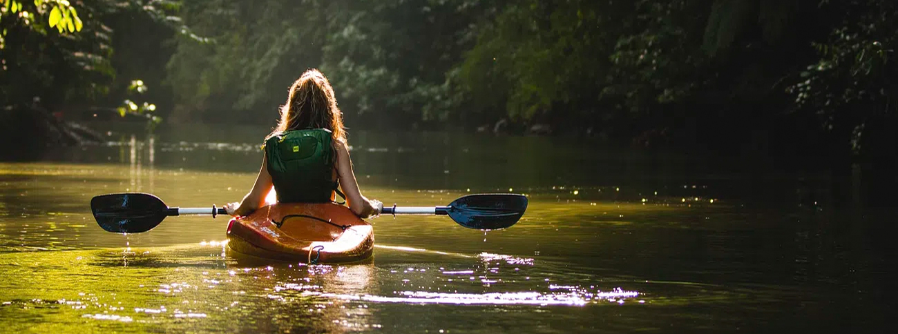 Women in kayak floating down stream 