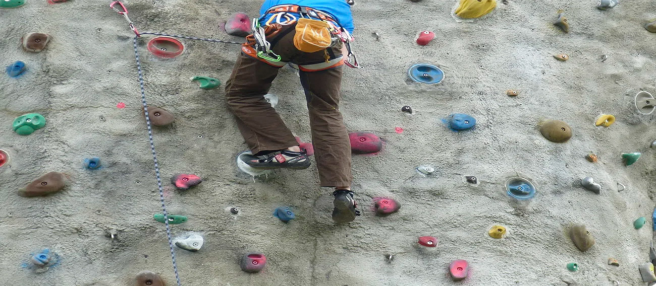 Man climbing with safety gear on indoor climbing wall