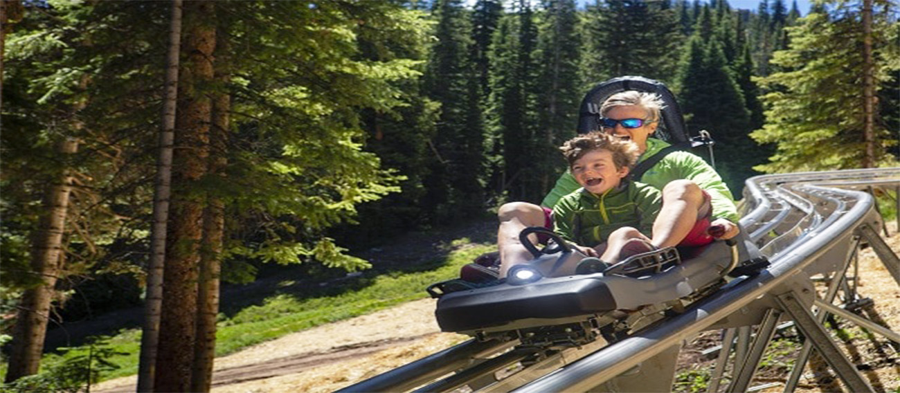 Women and young boy going down Snowmass Alpine Coaster during summer in Snowmass, Colorado