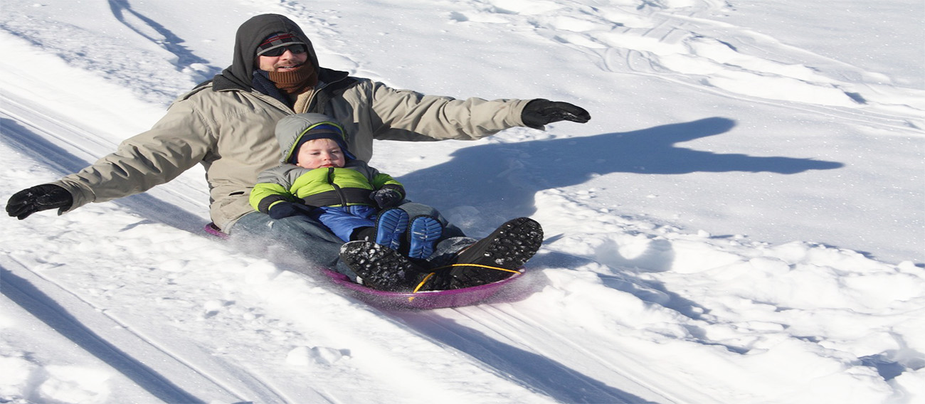 Father and Child Sledding down small hill
